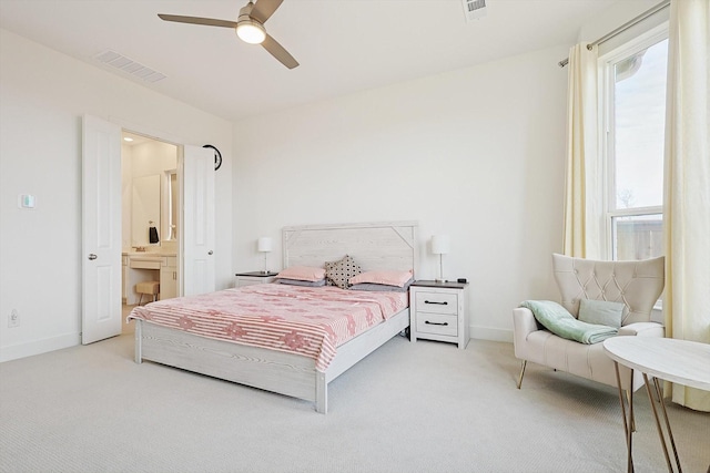 bedroom with connected bathroom, light colored carpet, and ceiling fan