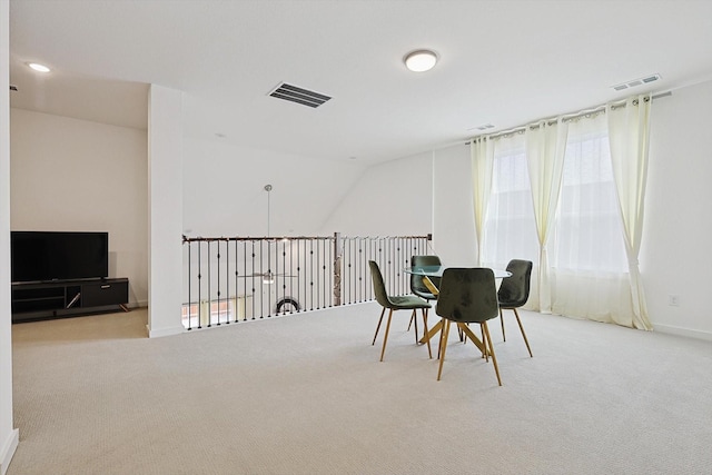 dining space with vaulted ceiling and light colored carpet