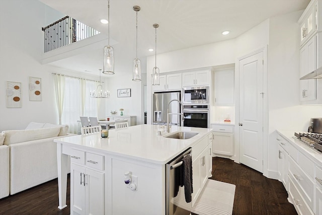 kitchen featuring sink, decorative light fixtures, appliances with stainless steel finishes, a kitchen island with sink, and white cabinets