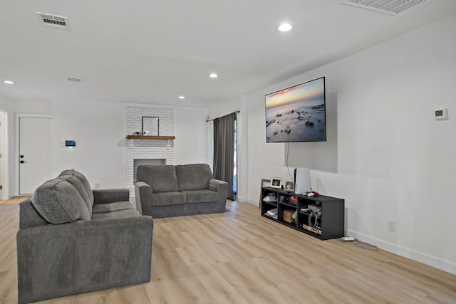 living room with a fireplace and light wood-type flooring