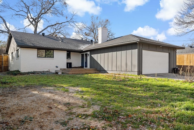 rear view of property featuring a garage and a yard