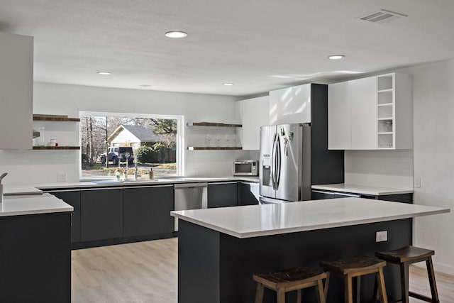 kitchen featuring sink, light hardwood / wood-style flooring, a breakfast bar, appliances with stainless steel finishes, and white cabinetry