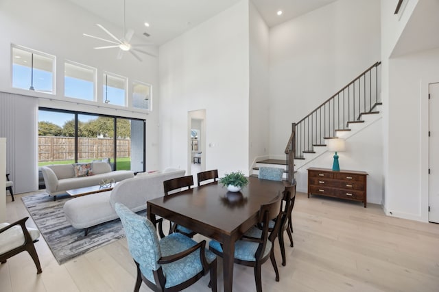 dining area featuring a towering ceiling and light hardwood / wood-style flooring