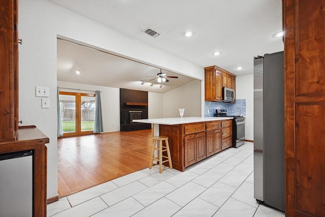 kitchen with ceiling fan, a kitchen breakfast bar, stainless steel appliances, lofted ceiling with beams, and kitchen peninsula