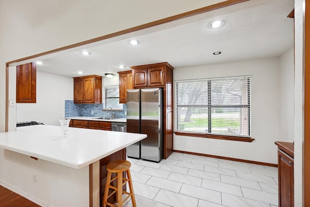 kitchen with tasteful backsplash, a kitchen bar, stainless steel appliances, and sink