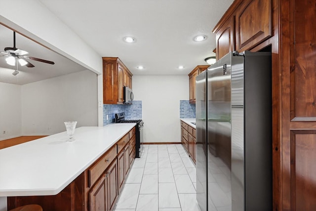 kitchen with a breakfast bar area, ceiling fan, appliances with stainless steel finishes, tasteful backsplash, and kitchen peninsula