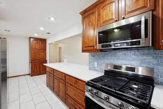 kitchen with light tile patterned flooring, appliances with stainless steel finishes, and backsplash