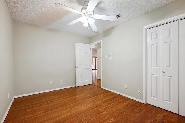 unfurnished bedroom featuring ceiling fan, wood-type flooring, a closet, and a textured ceiling