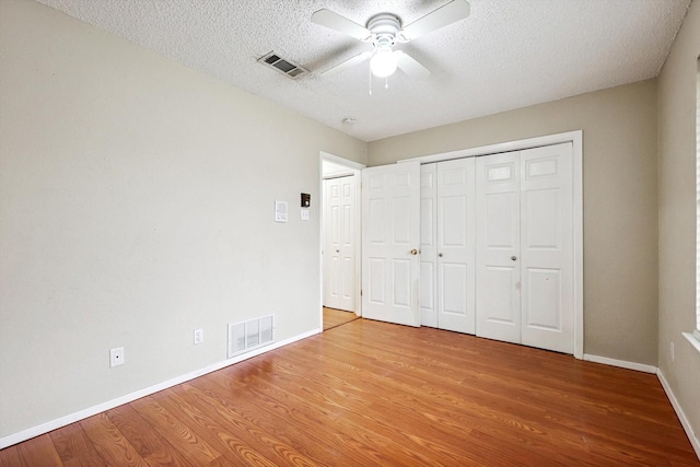 unfurnished bedroom with ceiling fan, wood-type flooring, and a textured ceiling