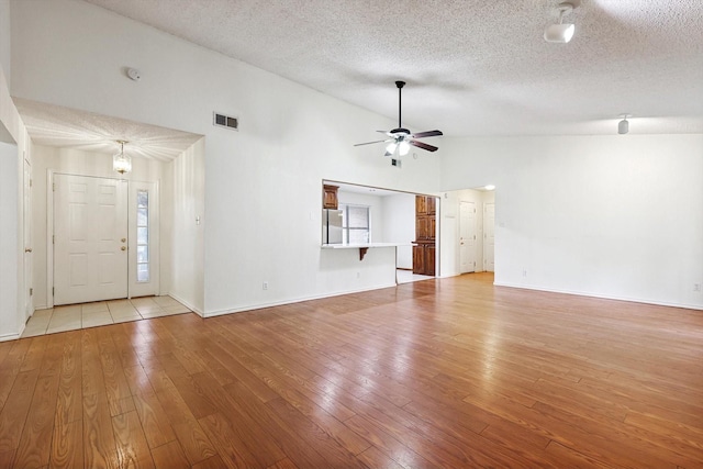 unfurnished living room with high vaulted ceiling, a textured ceiling, ceiling fan, and light hardwood / wood-style flooring