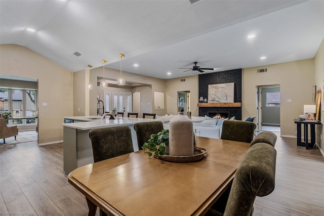 dining area featuring a healthy amount of sunlight, sink, a fireplace, and light hardwood / wood-style floors