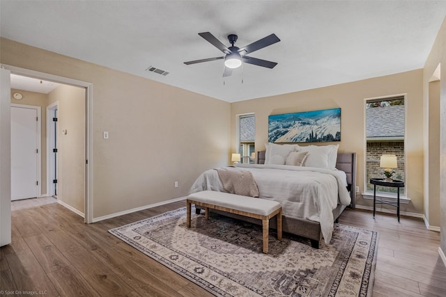 bedroom featuring multiple windows, hardwood / wood-style floors, and ceiling fan