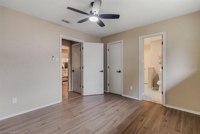 unfurnished bedroom with ensuite bath, light hardwood / wood-style floors, and ceiling fan