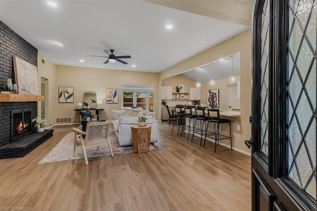 living room with a fireplace, light hardwood / wood-style floors, and ceiling fan