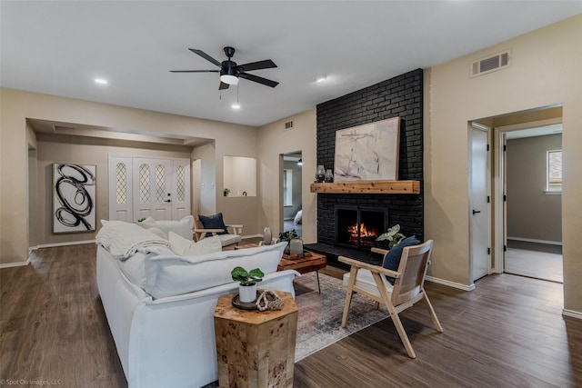 living room featuring ceiling fan, a fireplace, and dark hardwood / wood-style flooring