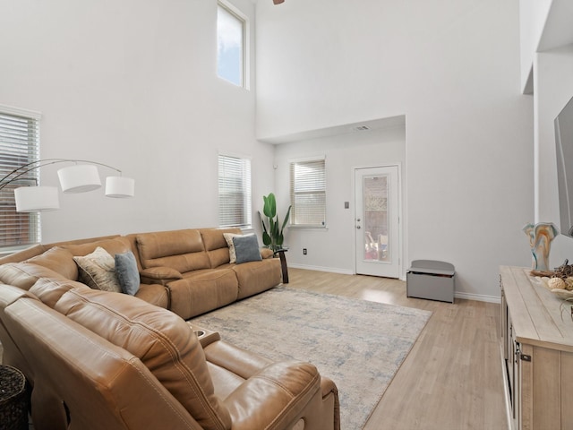 living room featuring a towering ceiling, light hardwood / wood-style floors, and a wealth of natural light