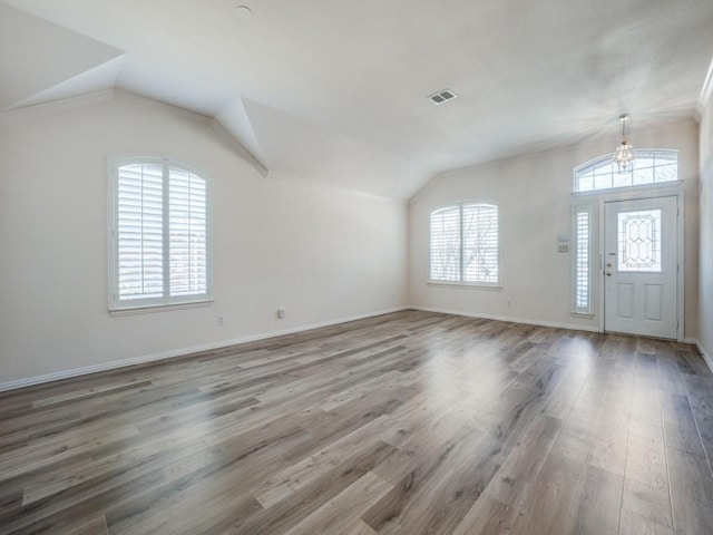 entryway with lofted ceiling, hardwood / wood-style flooring, and an inviting chandelier