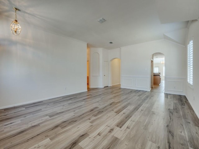 spare room featuring lofted ceiling and light wood-type flooring