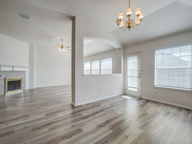 unfurnished living room featuring lofted ceiling, hardwood / wood-style flooring, a fireplace, and ceiling fan with notable chandelier