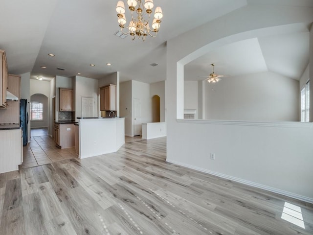 kitchen featuring vaulted ceiling, ceiling fan with notable chandelier, decorative light fixtures, sink, and light wood-type flooring