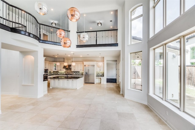 unfurnished living room featuring a towering ceiling, a wealth of natural light, and light tile patterned floors