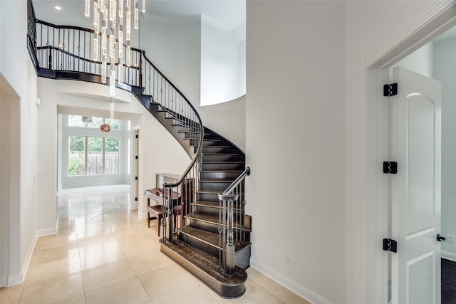 stairs featuring a towering ceiling, ornamental molding, and tile patterned floors