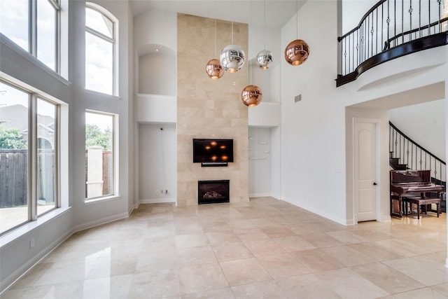 unfurnished living room featuring a high ceiling, light tile patterned floors, and a fireplace