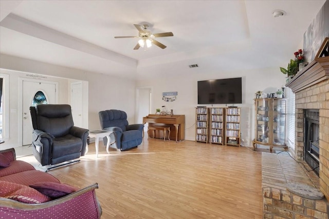 living room featuring light hardwood / wood-style flooring, a tray ceiling, and a fireplace