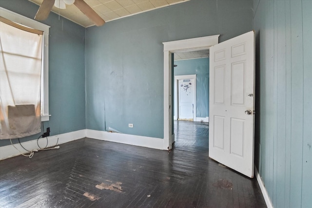 empty room featuring ceiling fan and wood walls