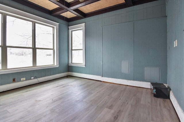 spare room with coffered ceiling, beam ceiling, and light wood-type flooring