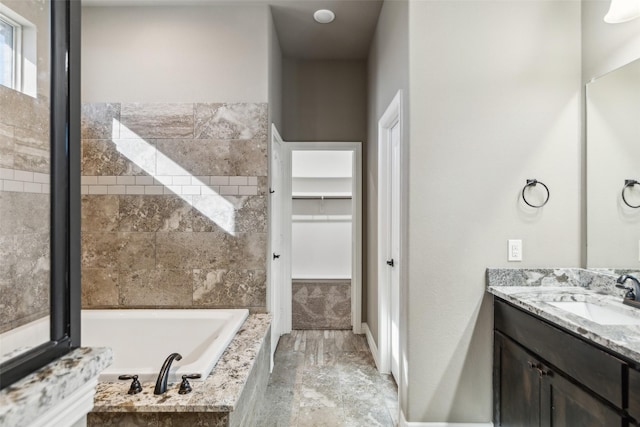 bathroom with vanity and tiled tub