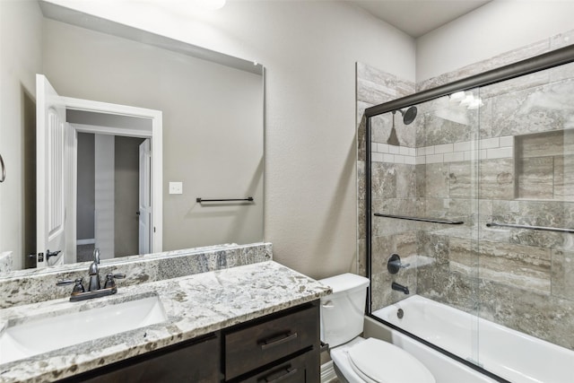 full bathroom featuring vanity, shower / bath combination with glass door, and toilet