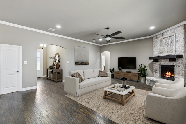 living room featuring a fireplace, crown molding, ceiling fan with notable chandelier, and dark hardwood / wood-style floors