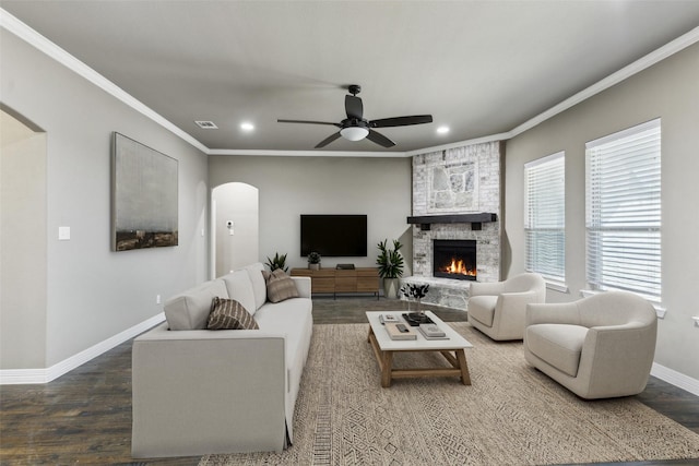 living room featuring wood-type flooring, plenty of natural light, ornamental molding, and a fireplace