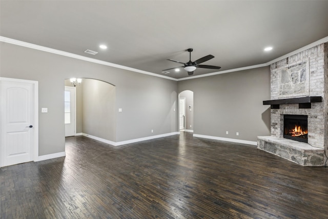 unfurnished living room with crown molding, a fireplace, ceiling fan with notable chandelier, and dark wood-type flooring