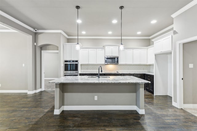 kitchen featuring a kitchen island with sink, sink, decorative light fixtures, and stainless steel appliances