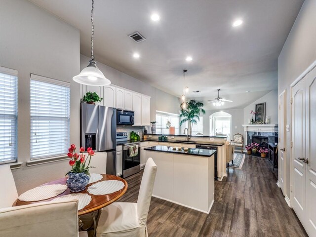 kitchen featuring pendant lighting, lofted ceiling, sink, white cabinets, and stainless steel appliances