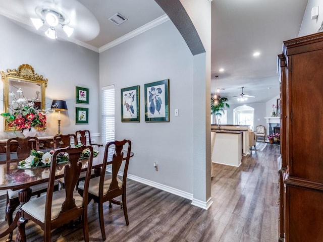 dining room with dark hardwood / wood-style flooring, ornamental molding, and ceiling fan