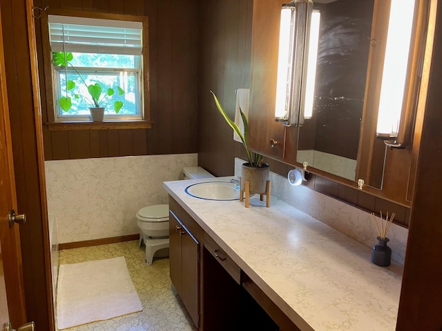 bathroom with vanity, toilet, and wood walls