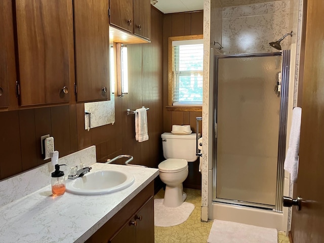 bathroom featuring vanity, a shower with door, toilet, and wood walls