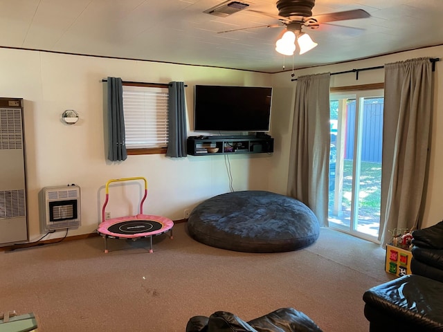 living area featuring heating unit, carpet floors, and ceiling fan