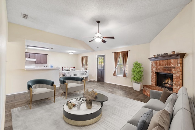 tiled living room with a brick fireplace, vaulted ceiling, a textured ceiling, and ceiling fan