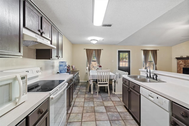 kitchen with dark brown cabinetry, sink, white appliances, and a textured ceiling