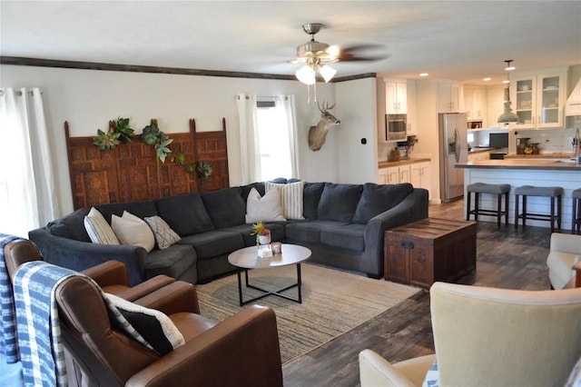 living room with crown molding, ceiling fan, and dark hardwood / wood-style floors