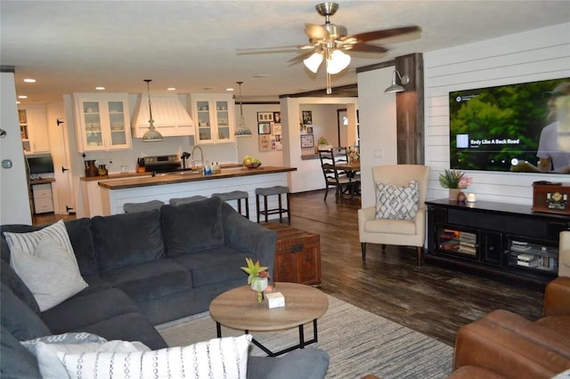 living room with wooden walls, dark hardwood / wood-style floors, and ceiling fan