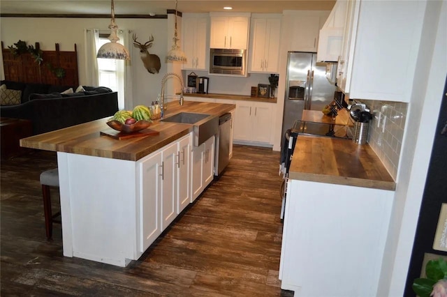 kitchen with wooden counters, stainless steel appliances, hanging light fixtures, and white cabinets