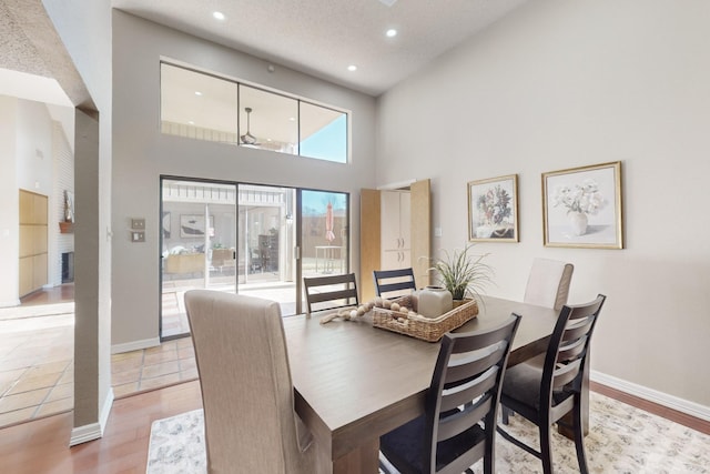 dining space with a towering ceiling and light hardwood / wood-style flooring