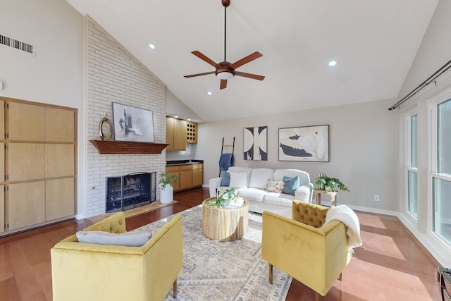 living room with ceiling fan, high vaulted ceiling, hardwood / wood-style floors, and a brick fireplace