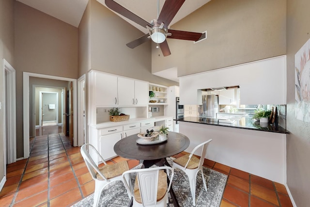 tiled dining area with ceiling fan, sink, and high vaulted ceiling