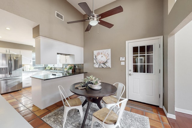 dining room with a towering ceiling, light tile patterned floors, and ceiling fan